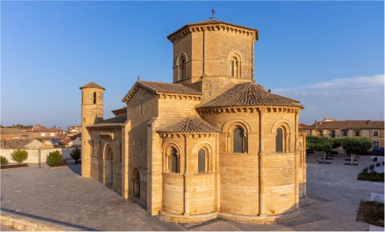Vista aérea en Fromista sobre la iglesia de San Martín: una cautivadora perspectiva y fascinante imagen tomada durante el amanecer. La Iglesia es uno de los monumento más emblemáticos de estilo románico con un torreón central, situado una plaza sin actividad con algunas casas en el fondo. 