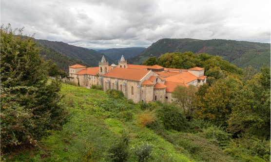 Monasterio de San Esteban de Ribas de Sil, situado en Nogueira de Ramuín, provincia de Ourense. Una imagen en la que se ve el gran tamaño del edificio del Monasterio con dos campanarios, situado entre montañas y con una gran cantidad de vegetación y árboles en un día nublado