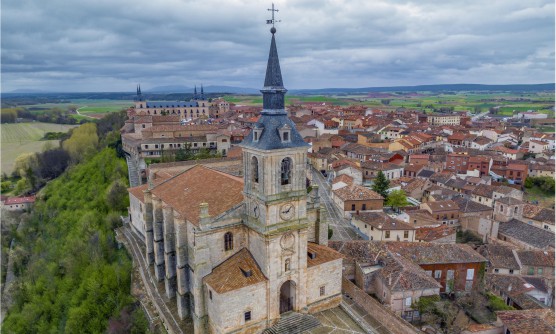 Preciosa vista aérea de la iglesia de San Pedro Lerma, en la que podemos contemplar como el pueblo se asienta sobre un cerro junto al río Arlanza. La iglesia de San Pedro se sitúa en lo alto del cerro y a sus pies se encuentran las viviendas y los campos verdes de cultivo. 