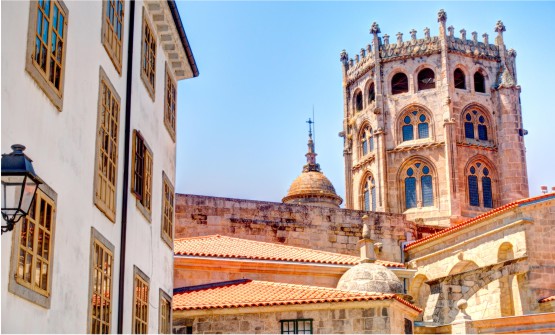 Vista parcial del la catedral de la ciudad de Ourense, en la que se ve un primer plano del cimborrio con ventanas de medio punto en cada uno de sus ocho lados. También se ve parte de la fachada de algunas casas que se encuentran delante de la catedral. 
